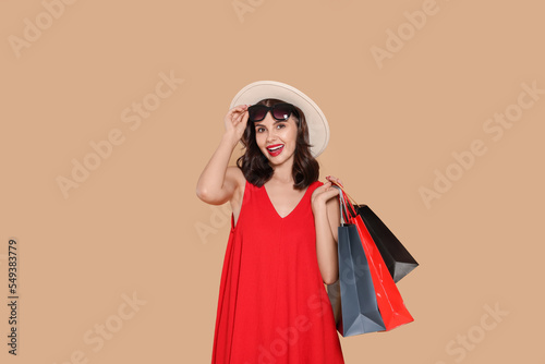 Beautiful young woman with paper shopping bags on beige background