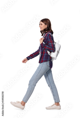 Happy young woman with stylish backpack walking against white background