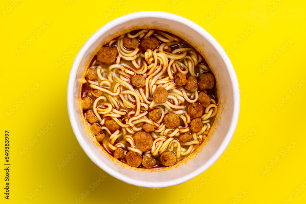 Instant noodles on cup isolated on yellow background