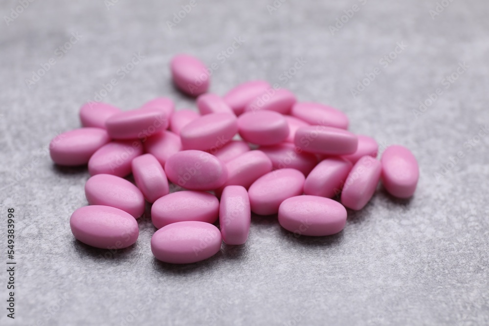 Many pink dragee candies on grey textured background, closeup Many pink dragee candies on grey textured background, closeup