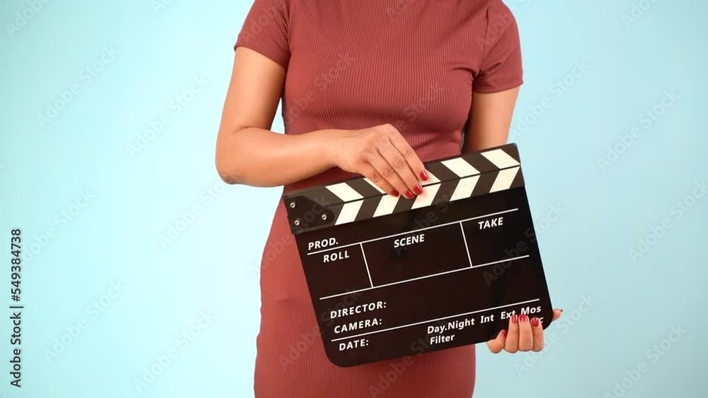 Hand is holding clapper board or clapperboard or movie slate, used in film production and cinema ,movies industry isolated over blue background.