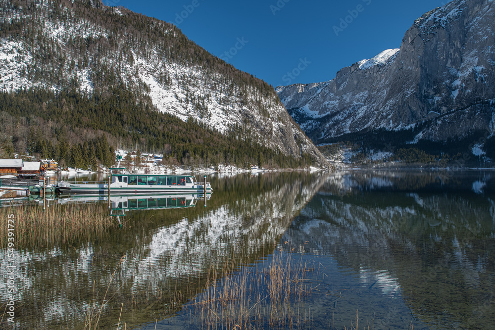 Sunny Winter Morning at Altausseersee, snowcaped mountains and wooden boathouse reflecting in crystal clear Mountain lake, Austria. Fog over water