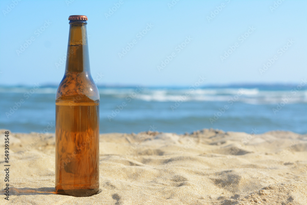Bottle of beer on sandy beach near sea. Space for text Bottle of beer on sandy beach near sea. Space for text