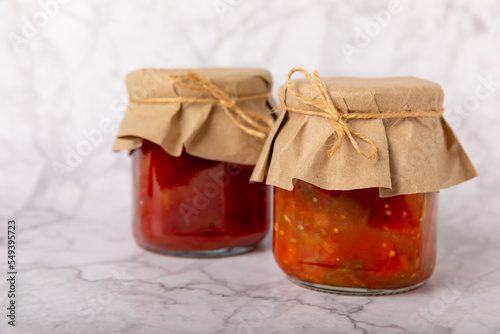 Glass jar of delicious canned lecho on a textured background. side view. Salad in a jar. Preservation for the winter. Place for text. Place to copy. photo