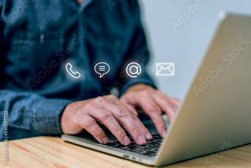 Hotline service, Customer support hotline Contact us people connection. Businessman using laptop with the email, call phone, address, Chat message icons photo