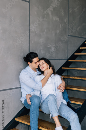 A young couple in love is sitting on the stairs of their house