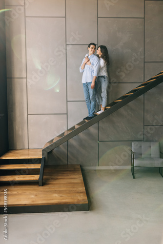 Young couple husband and wife at home sitting on the stairs hugging