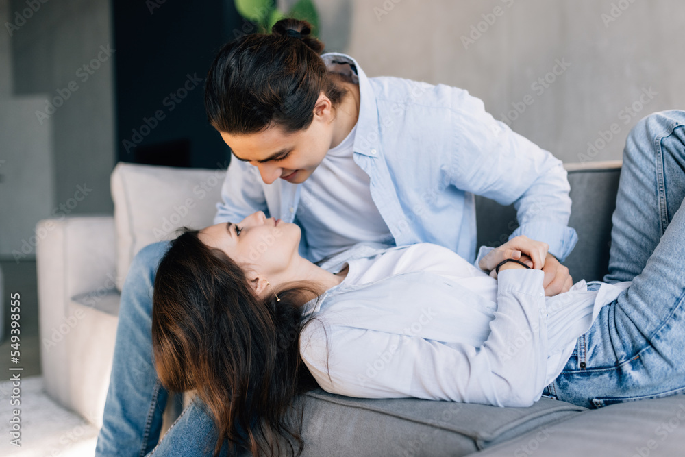 Loving relaxed young couple kissing in the living room at home Loving relaxed young couple kissing in the living room at home