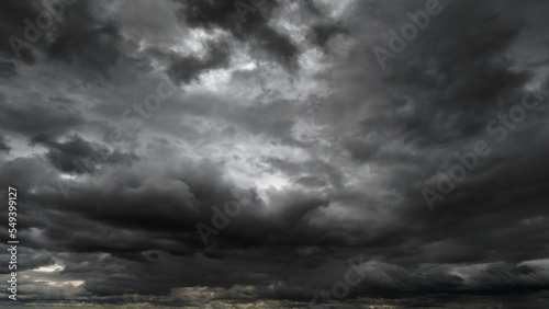 dark dramatic sky with black stormy clouds before rain or snow as abstract background, extreme weather, the sun shines through the clouds, high contrast photo