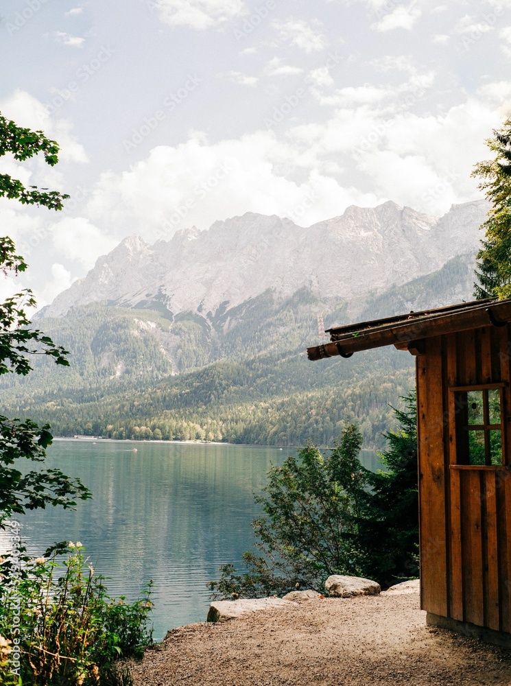 Obraz premium Wooden cabin near the clear lake with a mountain landscape view