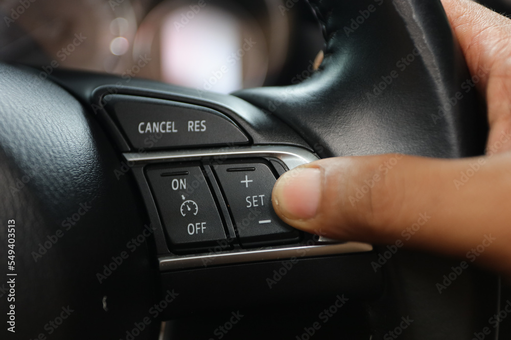 the driver's hand presses the cancel button to set the cruise control
