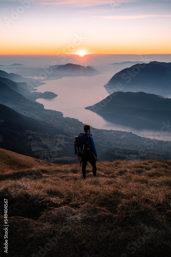 A hiker is walking on top of Punta Almana at sunset, with the Iseo Lake in the background, Northern Italy © Stefano Dosselli