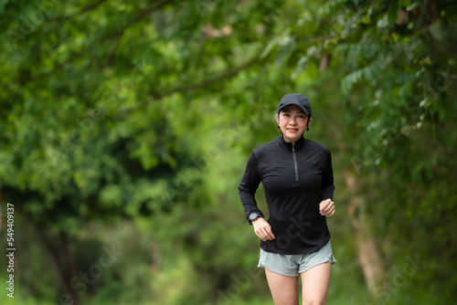 Healthy woman jogging run and workout on road outdoor. Asian runner people exercise gym with fitness session, nature park background. Health and Lifestyle Concept