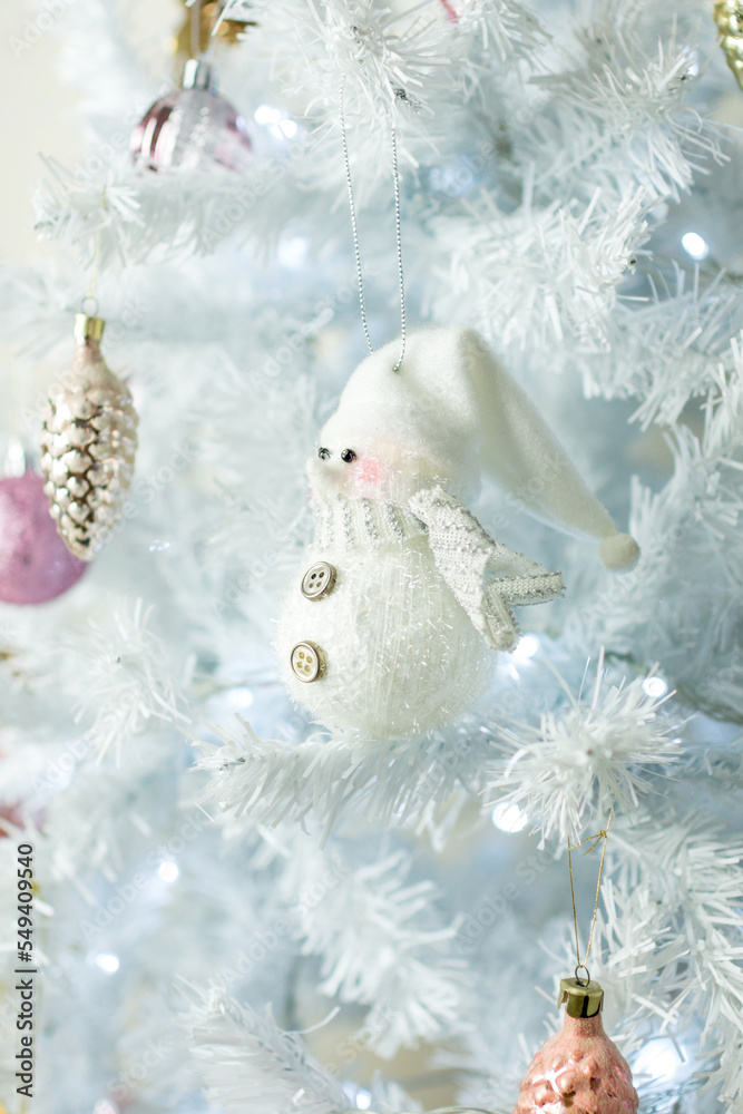 Christmas decorations. A snowman figurine on a white Christmas tree.