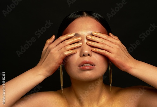 I don't see the evil. An Asian girl on a black background in a photo studio. Gold.