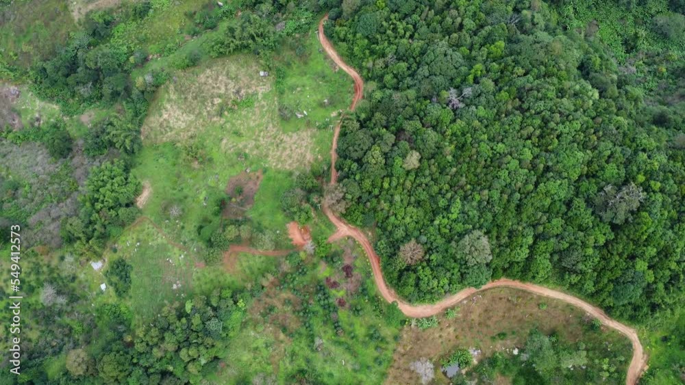 Aerial view from drone of mountain road with sun shining in forest. Top view of a road on a hill in a beautiful lush green forest in Thailand. Natural landscape background. Aerial view from drone of mountain road with sun shining in forest. Top view of a road on a hill in a beautiful lush green forest in Thailand. Natural landscape background.