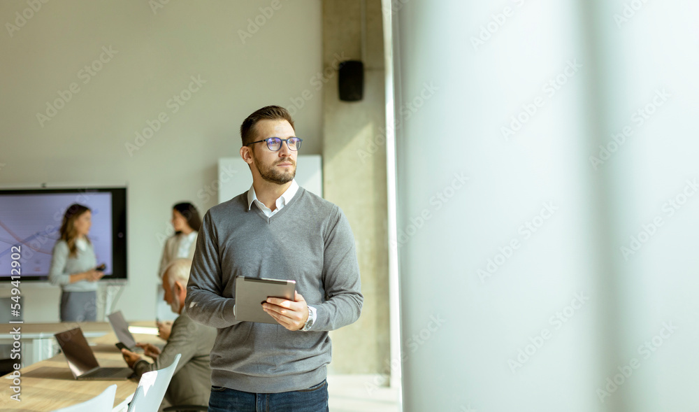Young modern businessman using digital tablet in the office