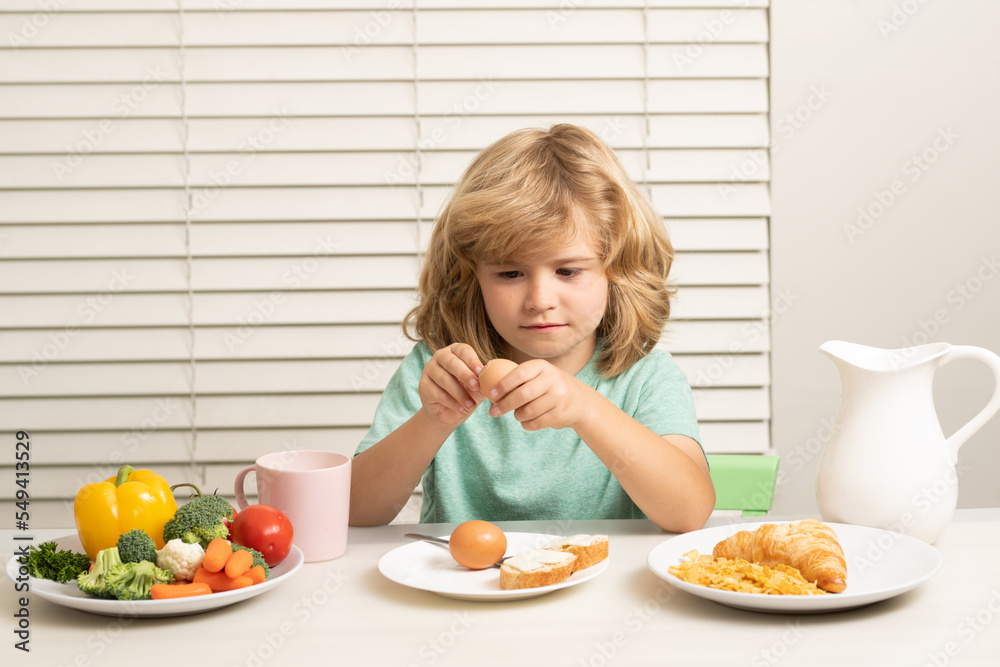 Child eating egg. Funny blonde little boy having breakfast. Milk, vegetables and fruits healthy food nutrition for children. Child eating egg. Funny blonde little boy having breakfast. Milk, vegetables and fruits healthy food nutrition for children.