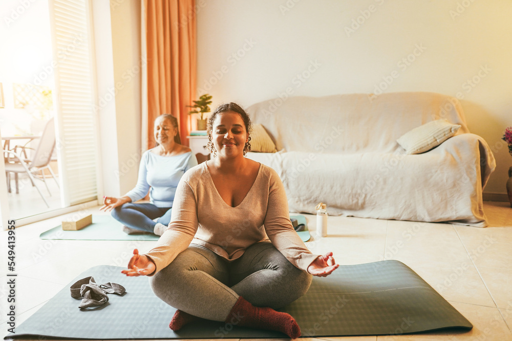 Mother and daughter doing yoga exercises at home together during winter time - Focus on girl face Mother and daughter doing yoga exercises at home together during winter time - Focus on girl face