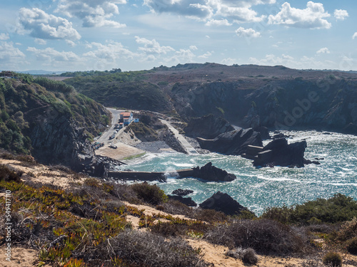 View of the small anchorage bay with fishing port at Azenha do Mar from the surrounding cliffs Odemira, Portugal. Sunny day, Clear blue sky. photo