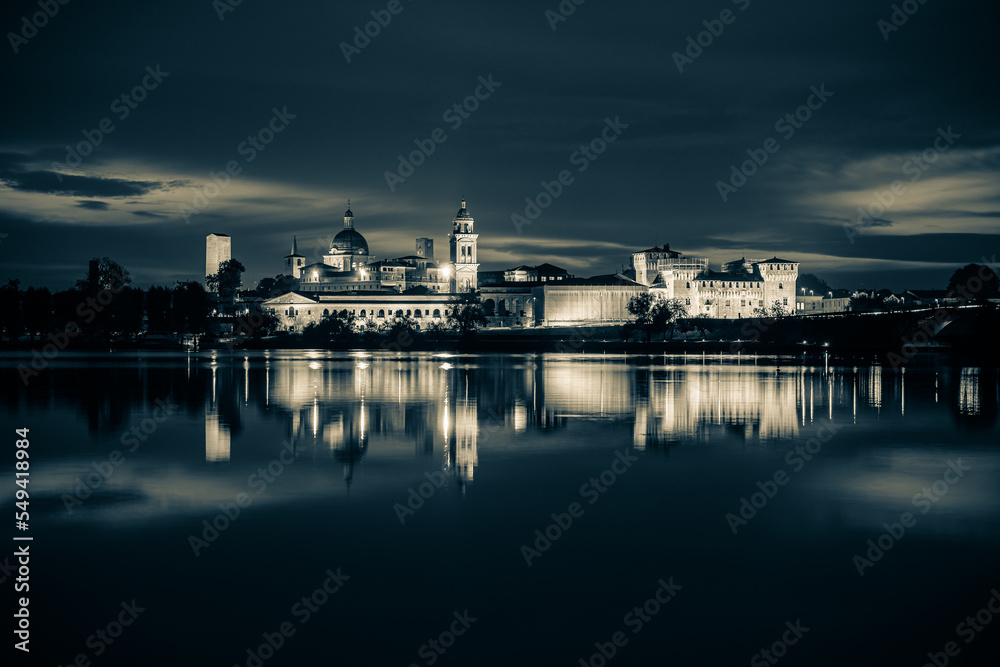 Panoramic evening view of Mantua, Lombardy, Italy; scenic twilight skyline view of the medieval town reflected in the lake waters