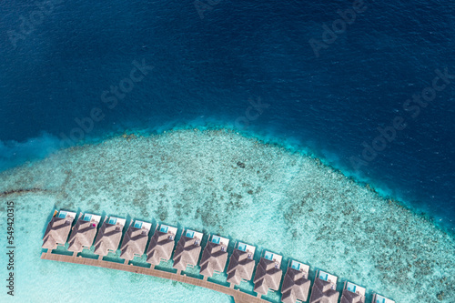 Maldives paradise vacation. Aerial holiday landscape, seascape with long pier, water villas and amazing sea lagoon bay, tropical nature. Exotic tourism destination. Top view bungalows ocean coral reef