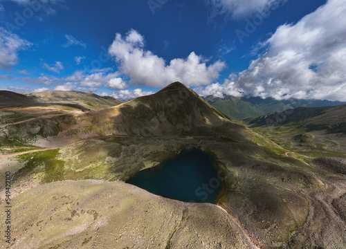 Aerial view of high mountain glacial lake and snow capped mountain peaks. Landscape of an alpine lake on a sunny day