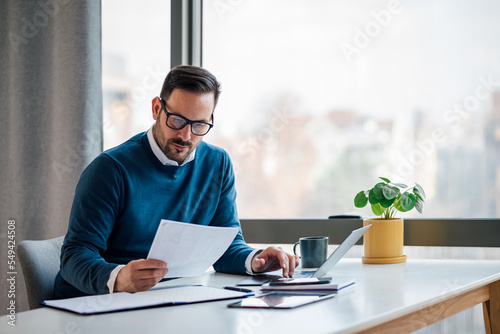 Картината върху платно Hardworking young adult businessman, checking the company budget in the files