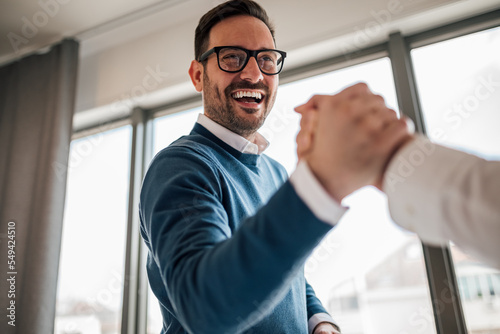 Excited young adult businessman, greeting a new member of his team.