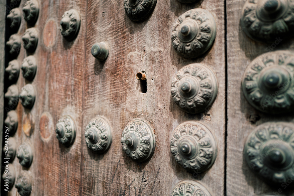 a keyhole from an ancient wooden door lined with an assortment of ornaments with rich contrast and bleu / green tones. The texture of the wood is deep and some areas are broken a keyhole from an ancient wooden door lined with an assortment of ornaments with rich contrast and bleu / green tones. The texture of the wood is deep and some areas are broken