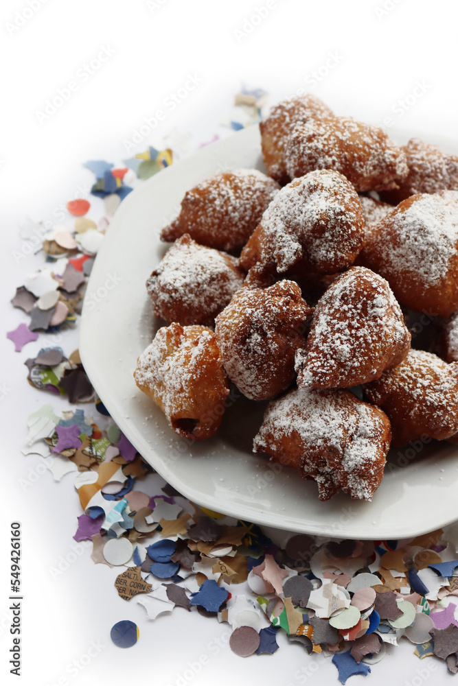 Traditional italian fritters filled with cream called Frittelle on a plate on white background with Confetti decorations Traditional italian fritters filled with cream called Frittelle on a plate on white background with Confetti decorations