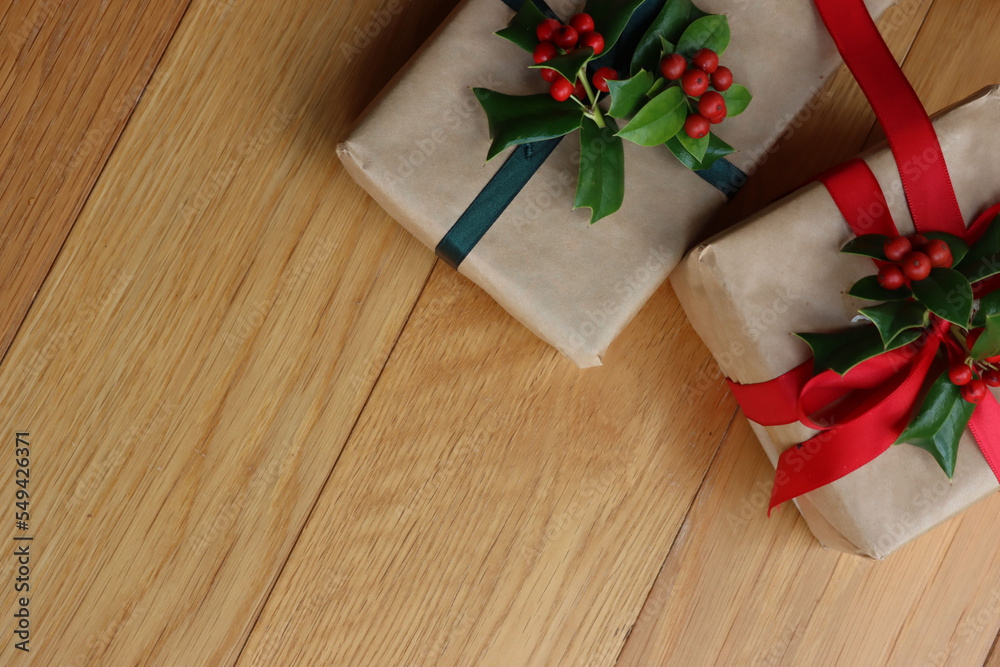 Two Christmas gifts with Holly decoration with red berries on a wooden background with copy space Two Christmas gifts with Holly decoration with red berries on a wooden background with copy space