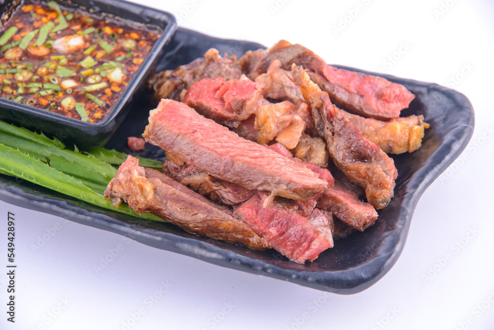 Roasted pork steak on the black plate with thai sauce.