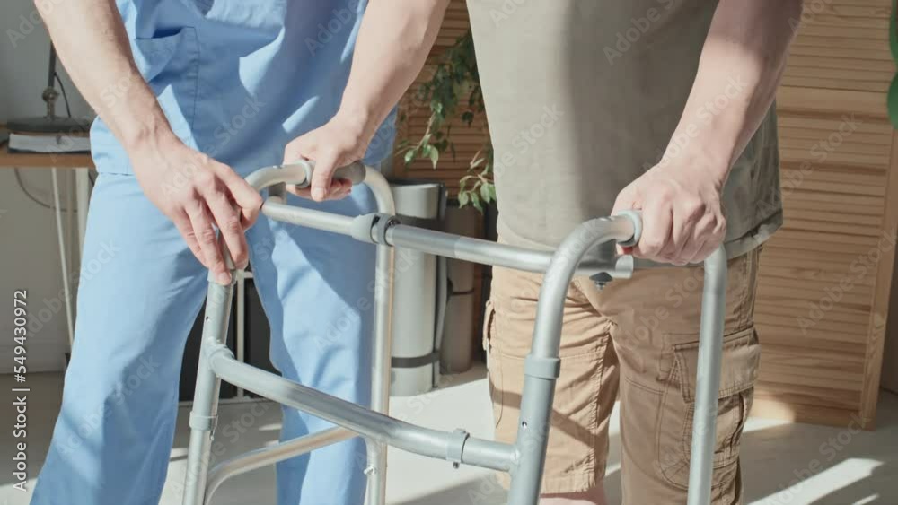 Close-up of doctor helping patient to use walker during his rehabilitation at hospital Close-up of doctor helping patient to use walker during his rehabilitation at hospital