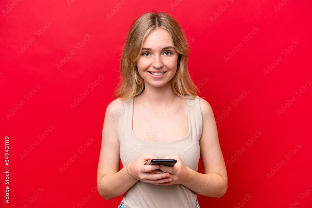 Young English woman isolated on red background sending a message with the mobile Young English woman isolated on red background sending a message with the mobile