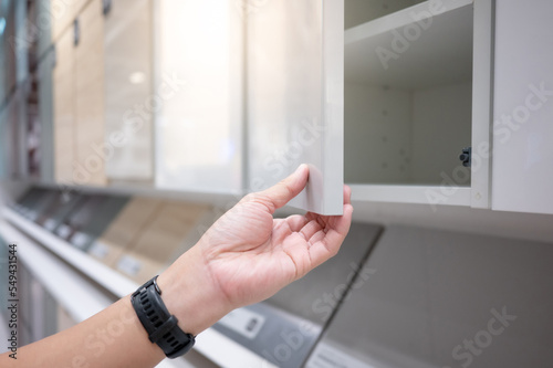 Fényképezés Male hand opening white cabinet door panel in furniture store