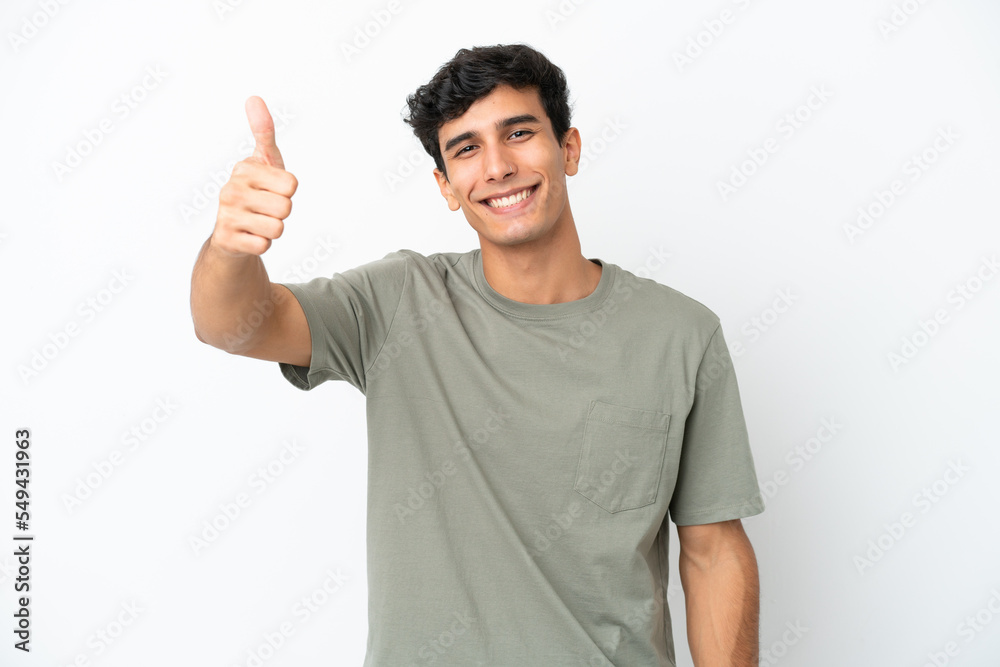 Young Argentinian man isolated on white background with thumbs up because something good has happened Young Argentinian man isolated on white background with thumbs up because something good has happened