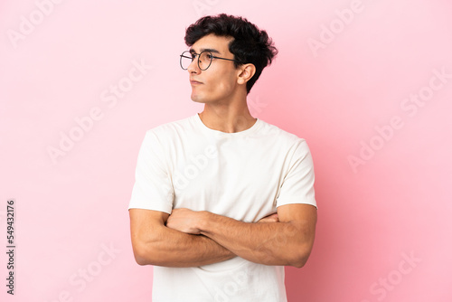 Young Argentinian man isolated on pink background looking to the side