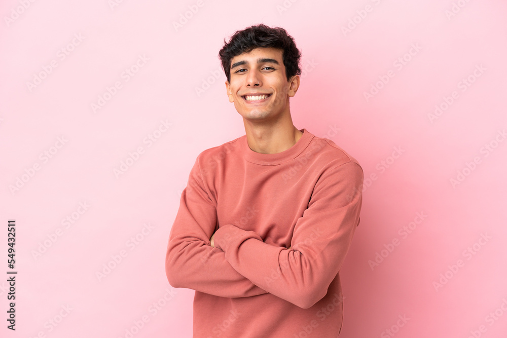 Young Argentinian man isolated on pink background with arms crossed and looking forward Young Argentinian man isolated on pink background with arms crossed and looking forward