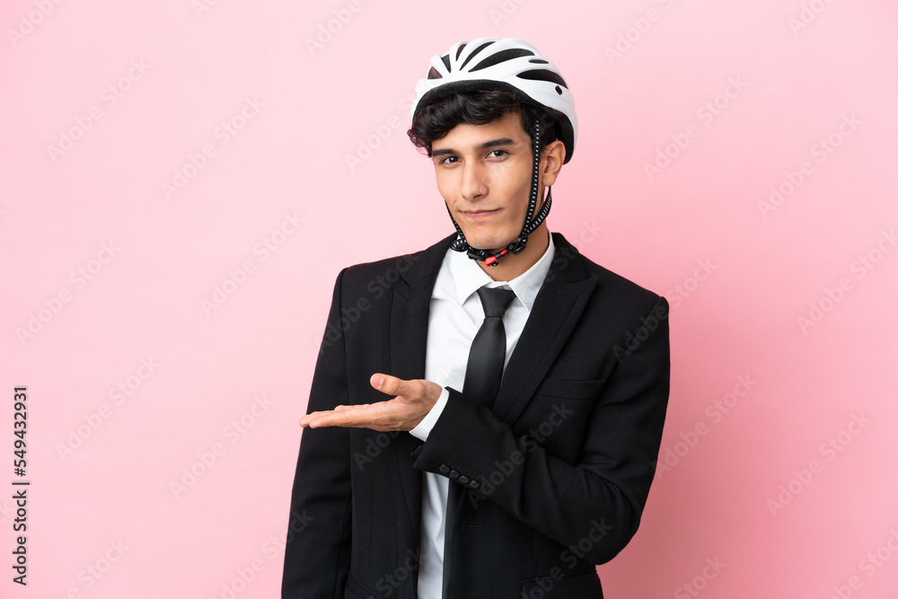 Argentinian businessman with bike helmen isoleted on pink background Argentinian businessman with bike helmen isoleted on pink background