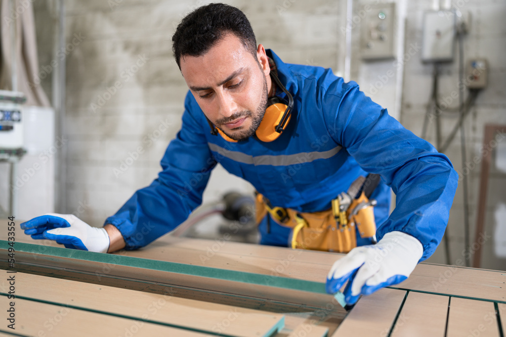 Handsome carpenter in safety uniform checking wood timber at wood factory Handsome carpenter in safety uniform checking wood timber at wood factory