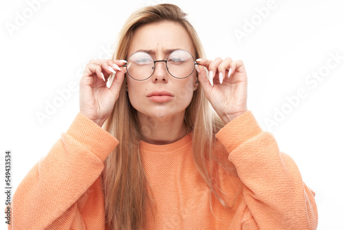 Blonde young woman wearing glasses squinting while looking at camera isolated on white background. Vision problems concept