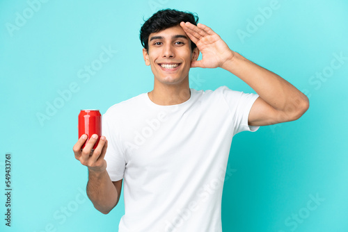 Young Argentinian man holding a refreshment isolated on blue background with surprise expression