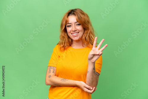 Young caucasian woman isolated on green screen chroma key background happy and counting three with fingers