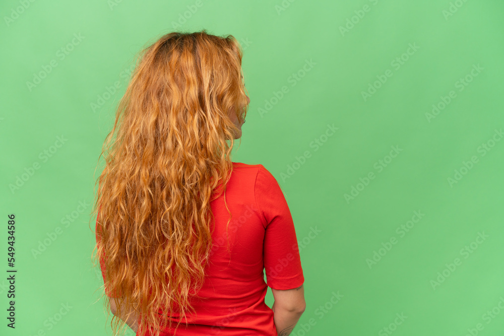 Young caucasian woman isolated on green screen chroma key background in back position and looking side Young caucasian woman isolated on green screen chroma key background in back position and looking side