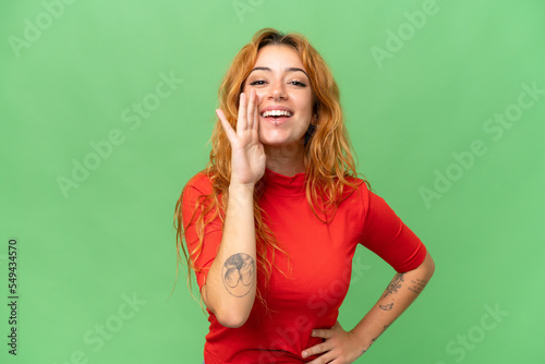 Young caucasian woman isolated on green screen chroma key background shouting with mouth wide open
