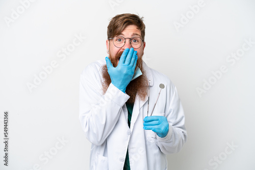 Dentist reddish man holding tools isolated on white background happy and smiling covering mouth with hand