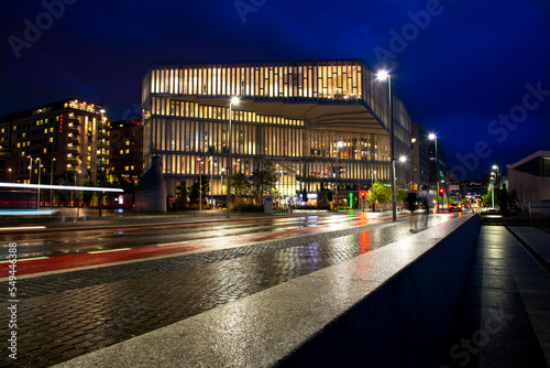 batiment moderne aux reflets dorés sur rue après la pluie aux heures bleues photo