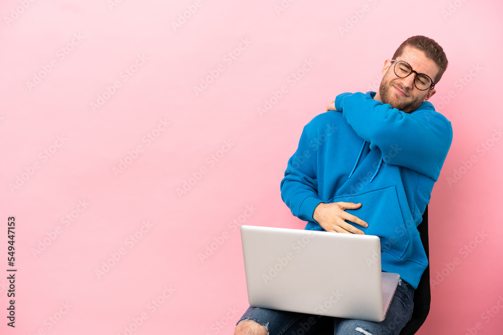 Young man sitting on a chair with laptop suffering from pain in shoulder for having made an effort Young man sitting on a chair with laptop suffering from pain in shoulder for having made an effort
