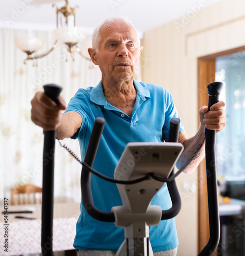 Male is working out on elliptical machine for elder healthy concept